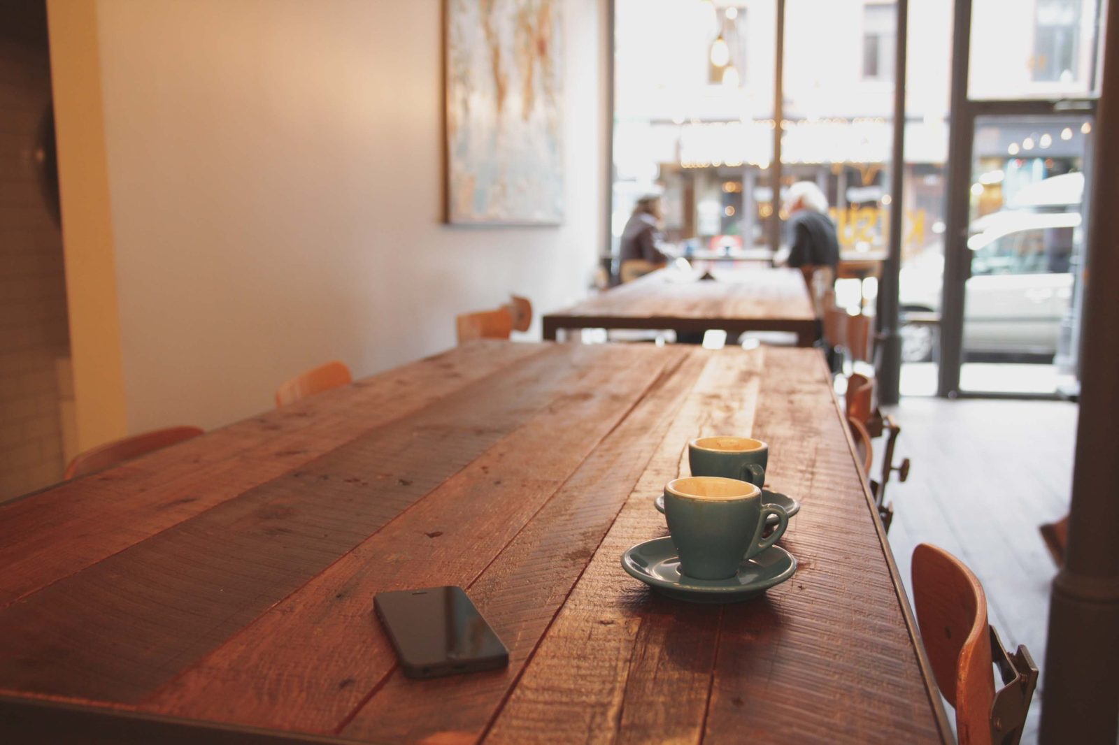 A quiet café table with two empty espresso cups, phone left behind