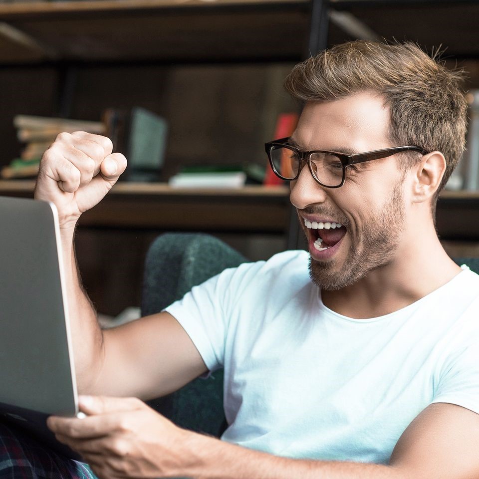 A business owner celebrating at his laptop